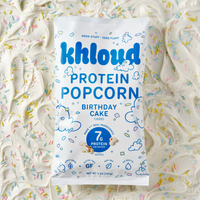 Khloud brand Birthday Cake protein popcorn bag on colorful sprinkle background.