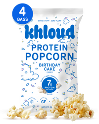 White package of Khlourd brand birthday cake flavored protein popcorn, 4 bags, with popcorn scattered in front.